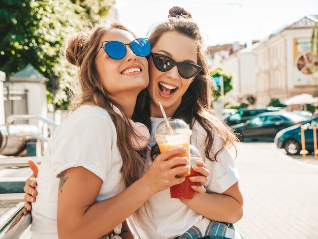 Two young beautiful smiling hipster female in trendy summer clothes