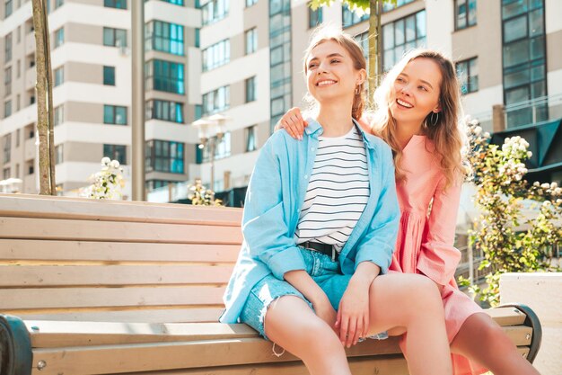 Two young beautiful smiling hipster female in trendy summer clothesSexy carefree women posing in the street Positive pure models having fun at sunset hugging and going crazy