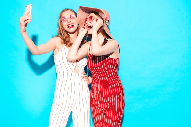 Two young beautiful smiling hipster female in trendy summer overalls clothes