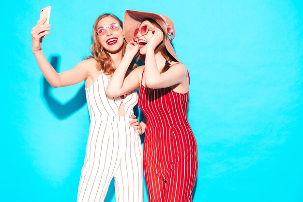 Two young beautiful smiling hipster female in trendy summer overalls clothes