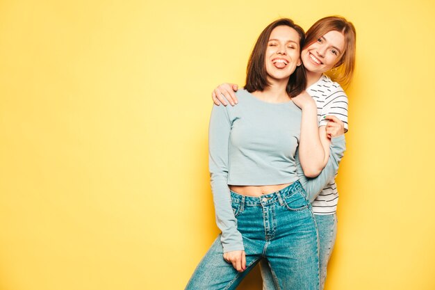 Two young beautiful smiling hipster female in trendy summer white t-shirt and jeans clothes