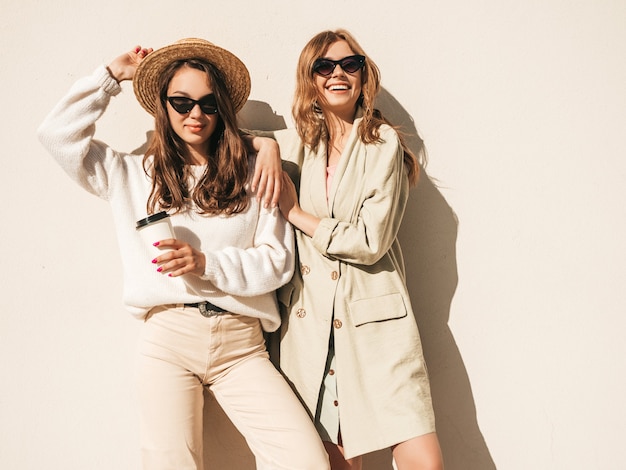 Free photo two young beautiful smiling hipster female in trendy white sweater and coat