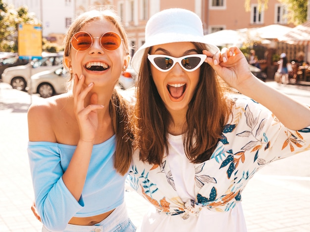 Two young beautiful smiling hipster girls in trendy summer clothes and panama hat. 