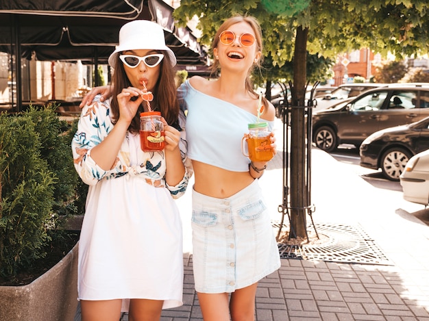 Due giovani belle ragazze sorridenti hipster in abiti estivi alla moda e cappello panama.