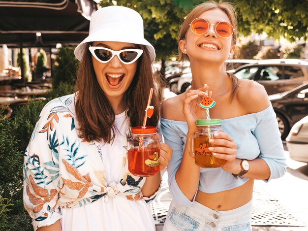 Two young beautiful smiling hipster girls in trendy summer clothes and panama hat.