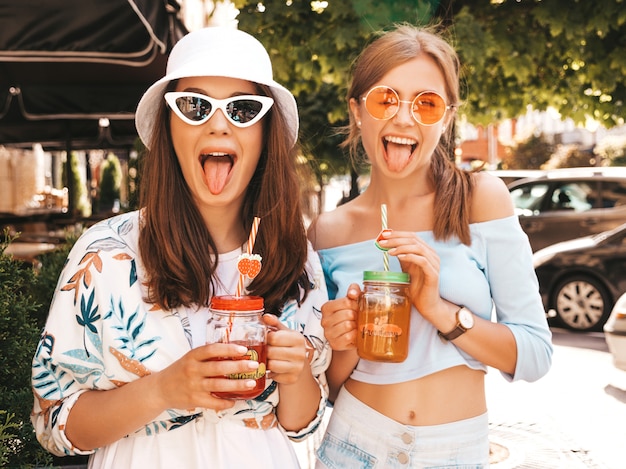 Due giovani belle ragazze sorridenti hipster in abiti estivi alla moda e cappello panama.