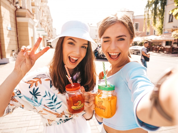 Free photo two young beautiful smiling hipster girls in trendy summer clothes