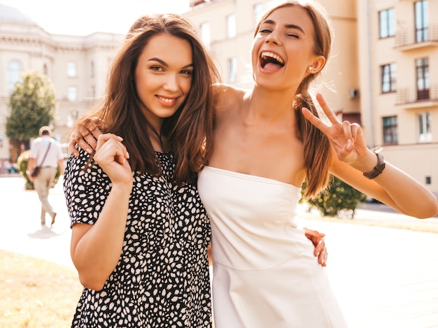 Two young beautiful smiling hipster girls in trendy summer clothes. 