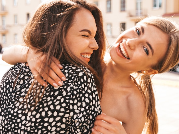 Two young beautiful smiling hipster girls in trendy summer clothes. 