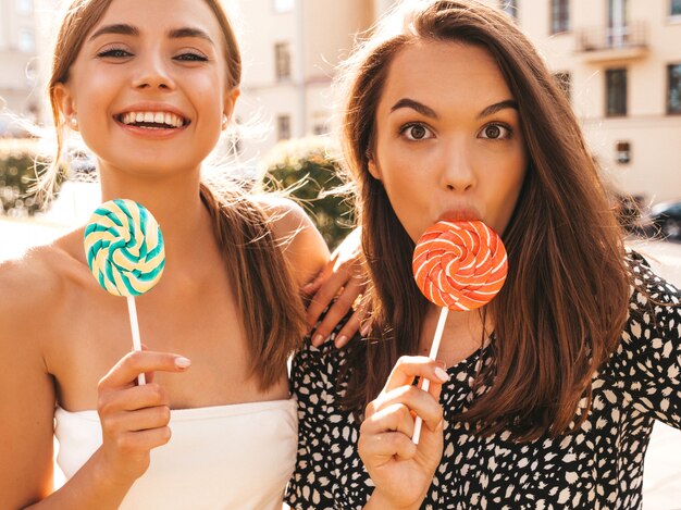 Two young beautiful smiling hipster girls in trendy summer clothes.