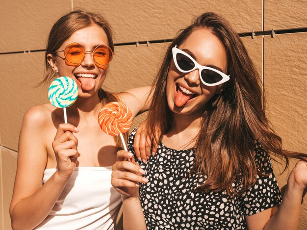 Two young beautiful smiling hipster girls in trendy summer dress.