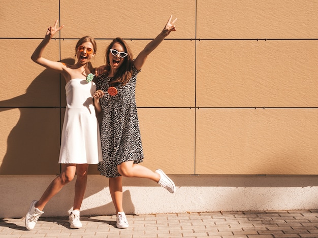 Free photo two young beautiful smiling hipster girls in trendy summer dress.