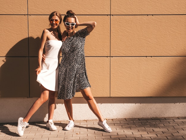 Free photo two young beautiful smiling hipster girls in trendy summer dress.