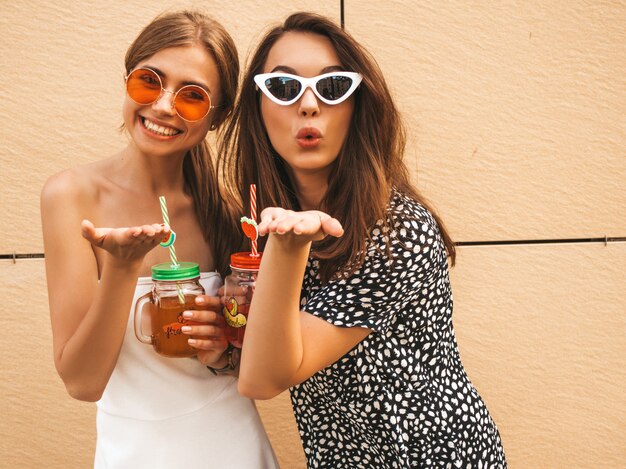 Two young beautiful smiling hipster girls in trendy summer dresses. 