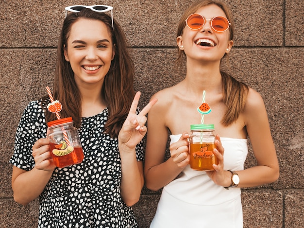 Two young beautiful smiling hipster girls in trendy summer dresses. 