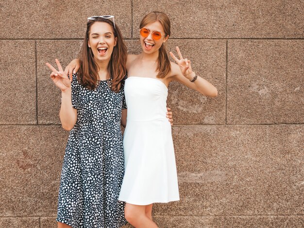 Две молодые красивые улыбающиеся битник девушки в модных летних платьях.