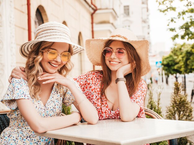 유행 여름 sundress에 두 젊은 아름 다운 웃는 hipster 여자. 선글라스에 거리 배경에 포즈 섹시 평온한 여자. 재미와 포옹을 가진 긍정적 인 모델