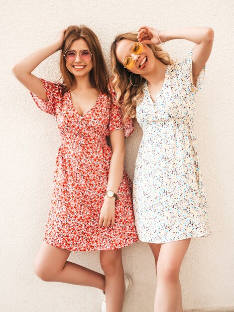 유행 여름 sundress에 두 젊은 아름 다운 웃는 hipster 여자. 선글라스에 벽 근처 거리에서 포즈 섹시 평온한 여자. 재미 있고 미쳐가는 긍정적 인 모델