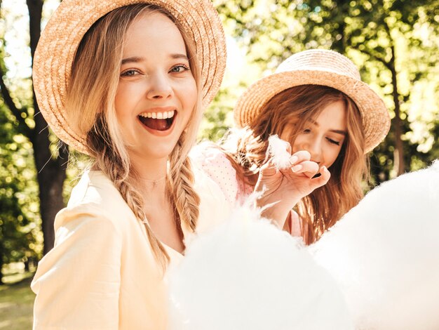 Two young beautiful smiling hipster girls in trendy summer sundress