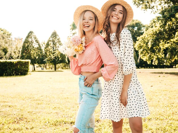 트렌디한 여름 sundress에 두 젊은 아름 다운 웃는 hipster 여자. 모자에 공원에서 포즈 섹시 평온한 여성.