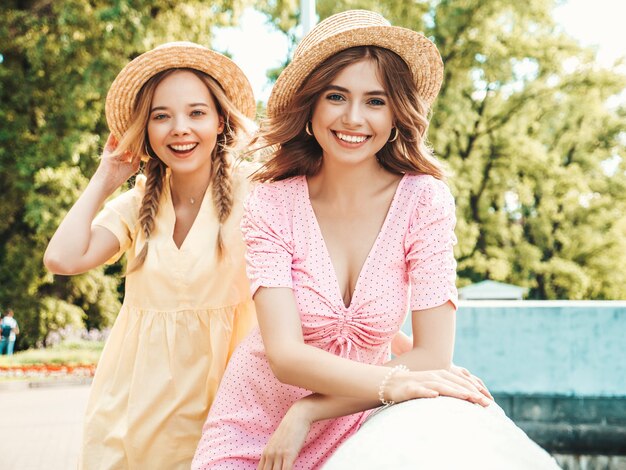 Two young beautiful smiling hipster woman in trendy summer sundress