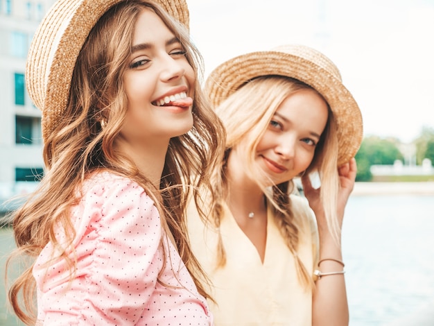 Две молодые красивые улыбающиеся хипстерские женщины в модном летнем сарафане
