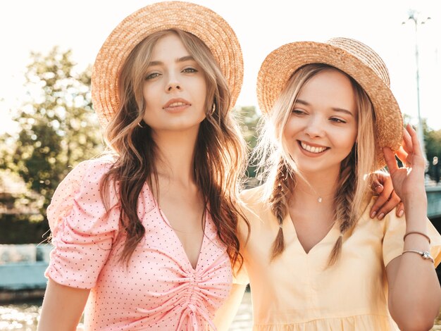 Two young beautiful smiling hipster woman in trendy summer sundress