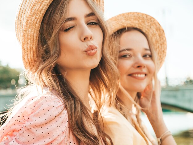 Two young beautiful smiling hipster woman in trendy summer sundress