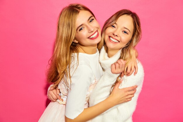 Две молодые красивые улыбающиеся женщины в модных летних белых одеждах