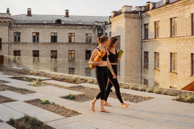 Two young beautiful women in sportswear going to do sports training, gymnastics, yoga