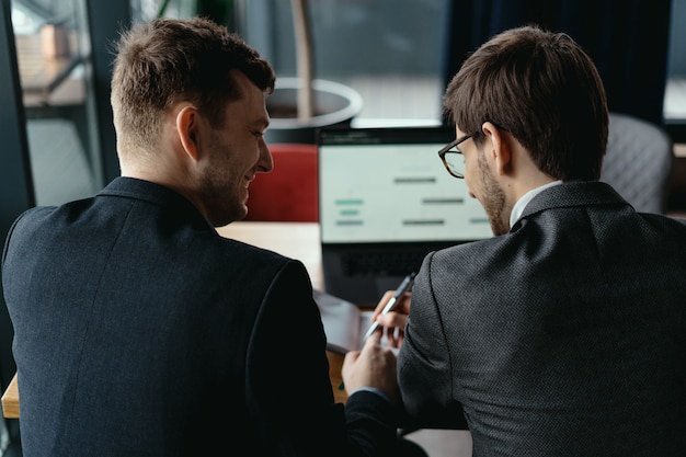 Free photo two young businessman having a successful meeting at restaurant.