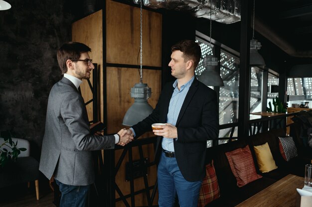 Two young businessmen greeting each other, shaking hand