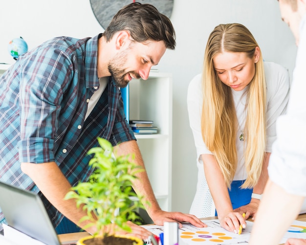 Two young businesspeople looking at graph over desk