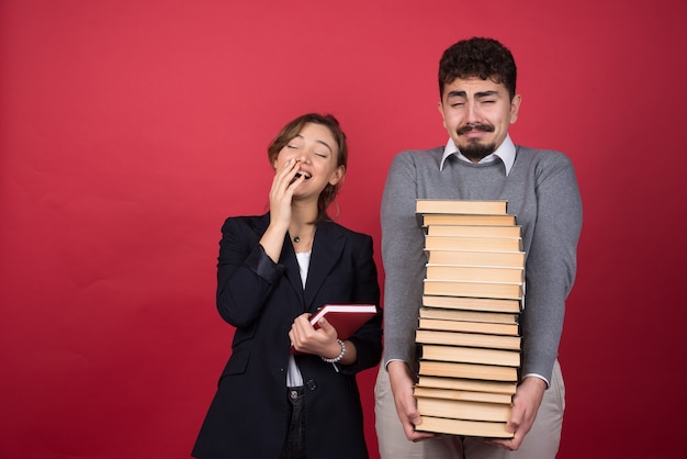 Two young businesspeople with books feeling tired