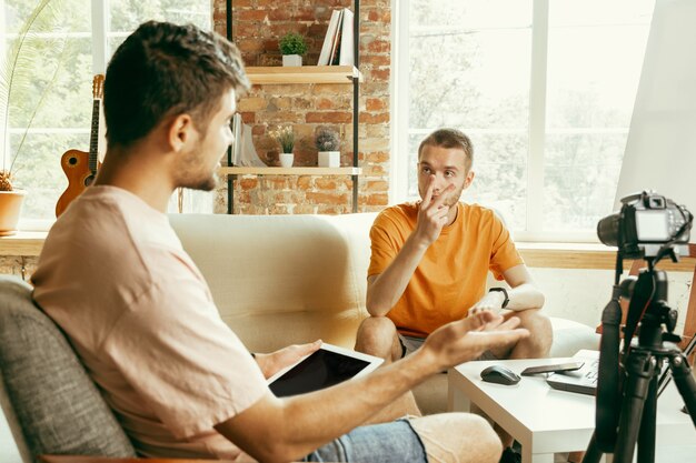 Two young caucasian male bloggers in casual clothes with professional equipment