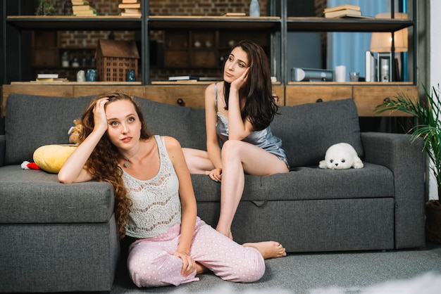 家に座っている2人の若い熟考された女性