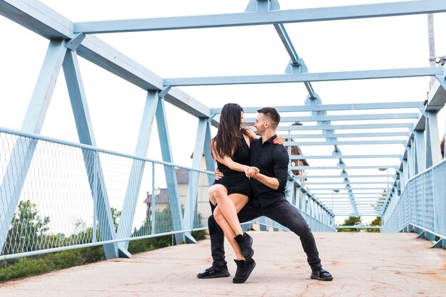 Two young couple dancing over the bridge