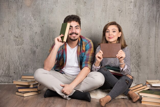 Two young couple posing with bunch of books