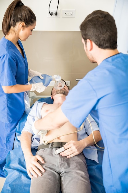 Free photo two young doctors performing cpr on a patient using a defibrillator and ambu bag in a hospital