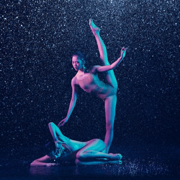 Two young female ballet dancers under water drops