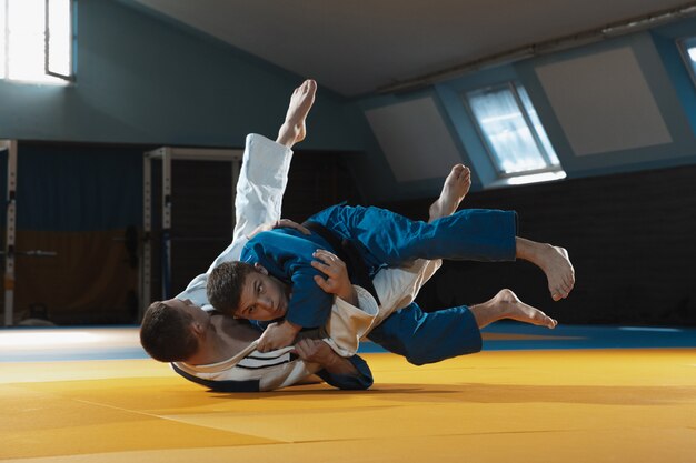 Two young fighters in kimono training martial arts in the gym