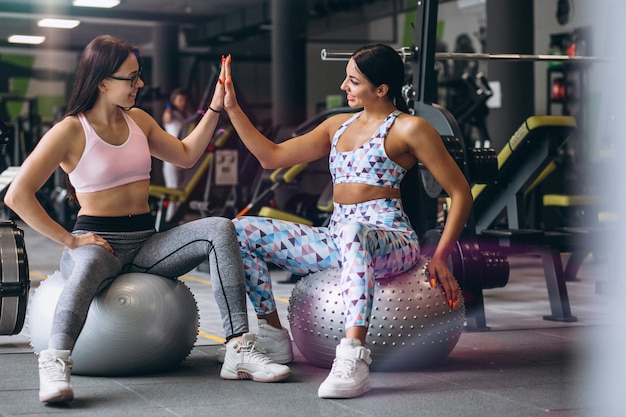 Two young girls training at gym sitting on fitness ball