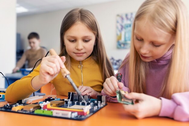 Two young girls using electronic parts to build a drone