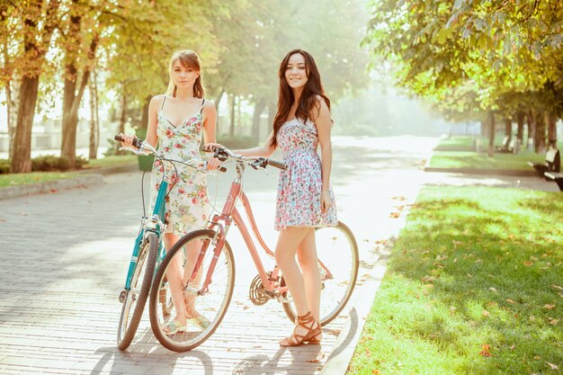 The two young girls with bicycles in park