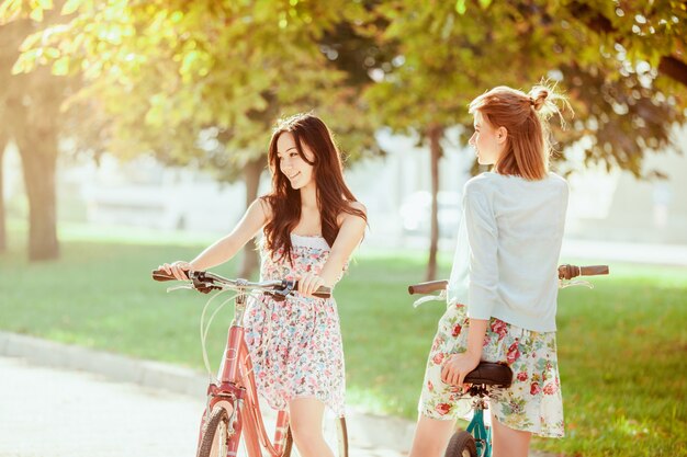 Две молодые девушки с велосипедами в парке