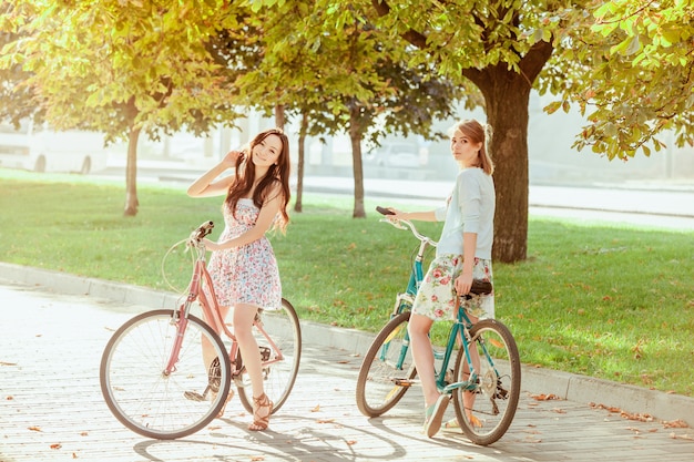 The two young girls with bicycles in park