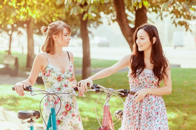 две молодые девушки с велосипедами в парке