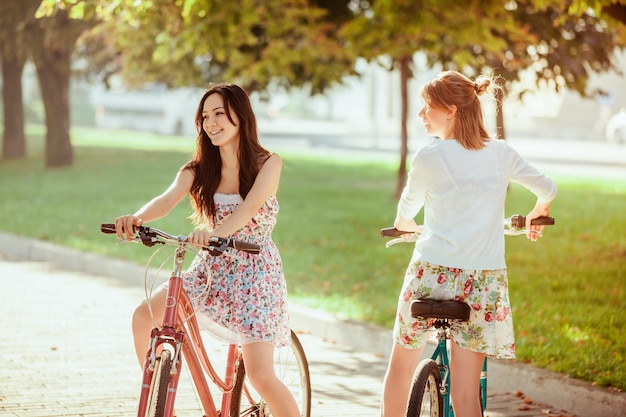 две молодые девушки с велосипедами в парке