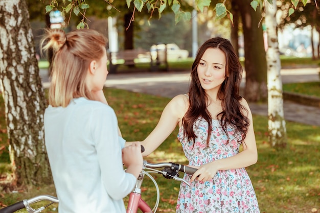 Due giovani ragazze con le biciclette nel parco