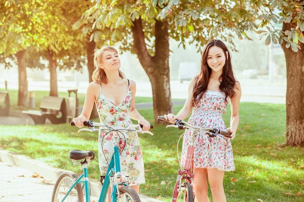 The two young girls with bicycles in park